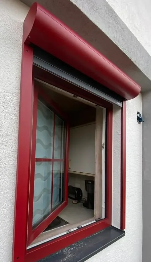 Dasselbe Fenster mit fertig montiertem Rollladen in passendem Rot
