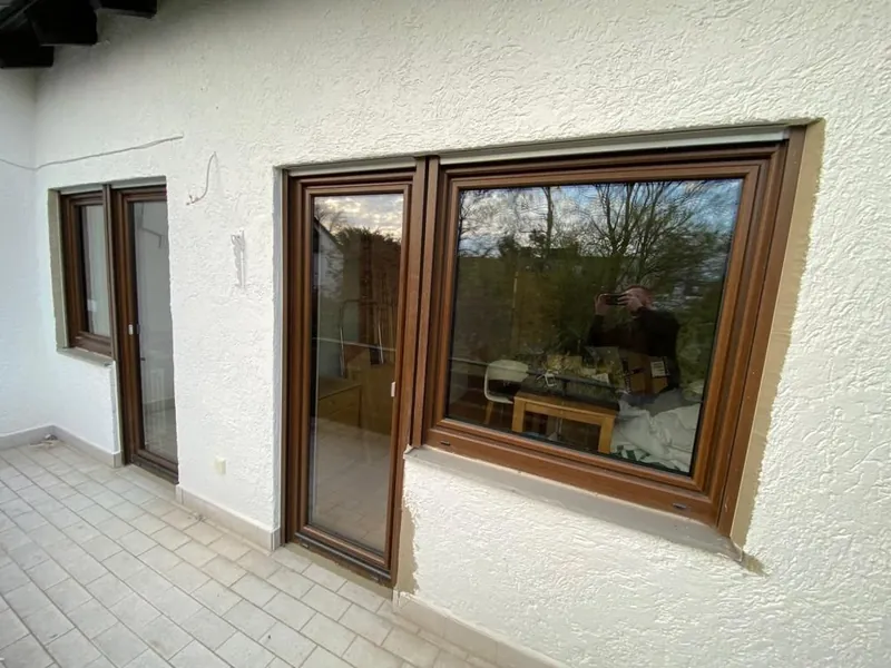 Fenster in Holzdekor in einer weißen Putzfassade