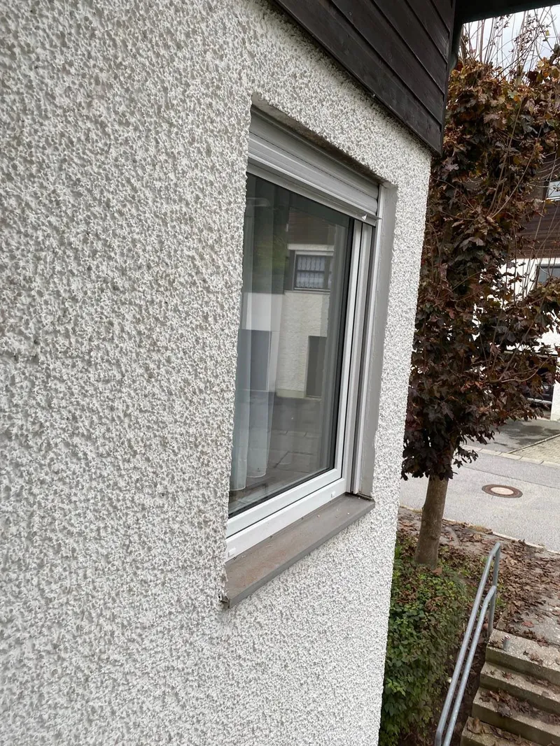 Weißes Kunststofffenster in einer verputzten Fassade