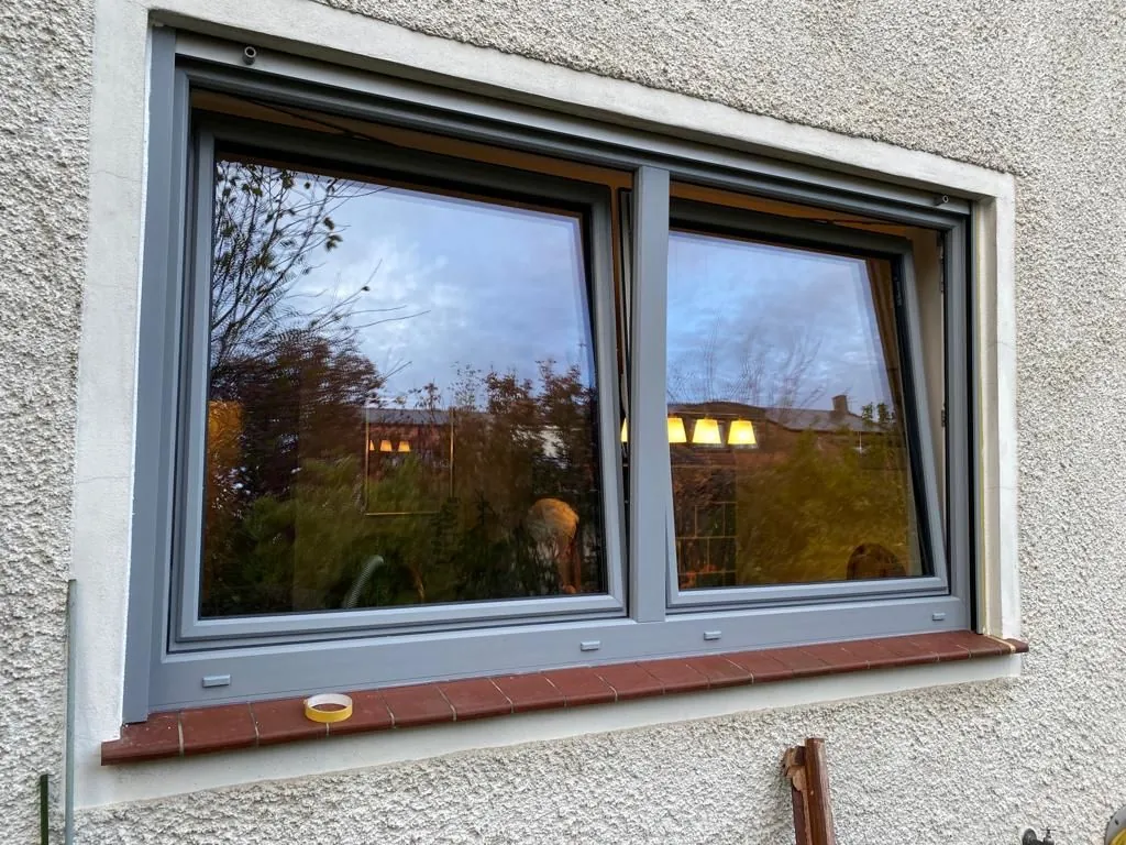Großes Fenster mit grauem Rahmen in der Abenddämmerung
