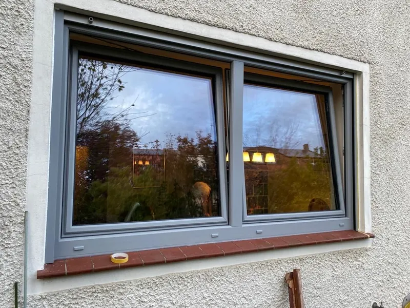 Großes Fenster mit grauem Rahmen in der Abenddämmerung